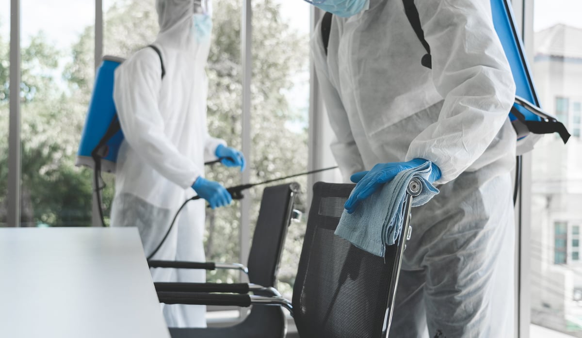 Man in virus protective suit and mask spraying alcohol cleaning covid19 infected area